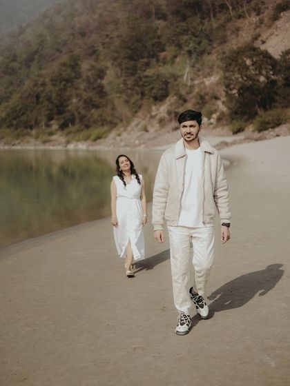 A stylish shot of a couple walking along the riverbank, capturing a natural and unposed moment.