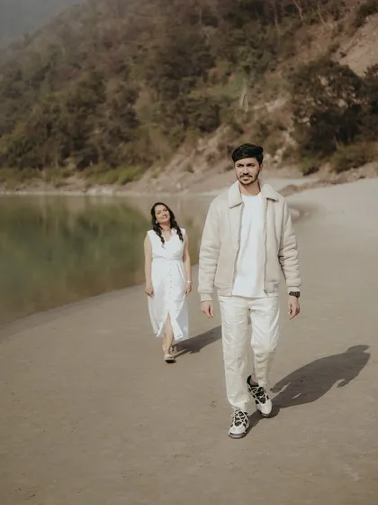 A stylish shot of a couple walking along the riverbank, capturing a natural and unposed moment.