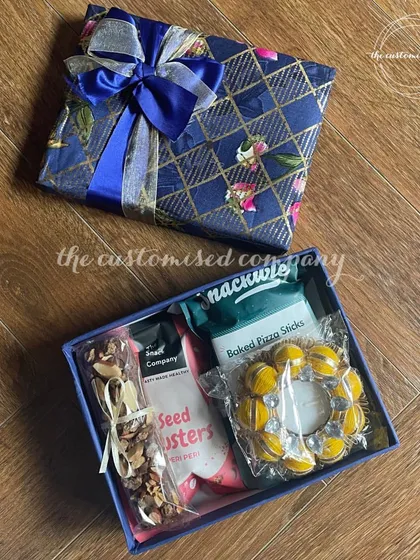 I offer budget-friendly options that don't compromise on style. This compact hamper includes healthy seed clusters, baked pizza sticks, and a diya, beautifully wrapped for corporate or personal gifting.