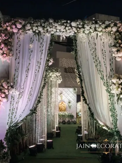 A grand entrance draped in white florals and soft fabrics. This design creates a beautiful, layered effect, making the transition into the event space feel like stepping into another world.