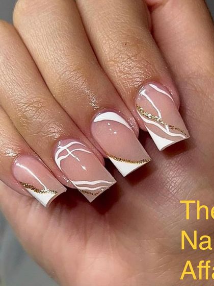 An elegant design on square nails, featuring abstract white and gold glitter lines over a sheer nude base.