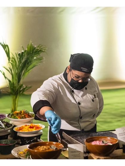 A female chef at a live station, preparing a dish with focus and expertise. We celebrate the talent and dedication of all members of our diverse culinary team.