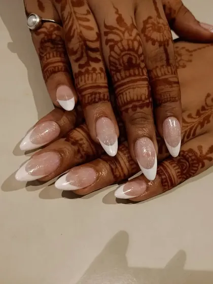 A classic and timeless choice for any bride. This is a perfectly executed French manicure with a sparkling base on long, almond-shaped nails, shown with bridal henna.