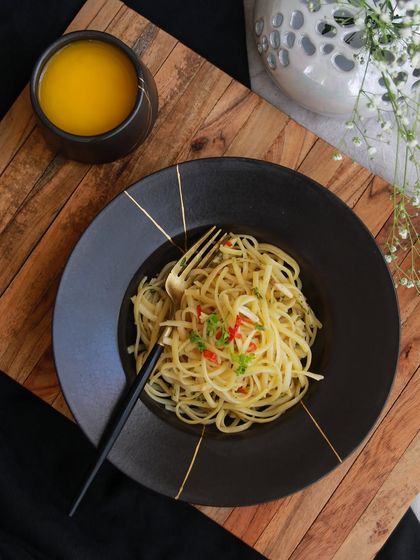 A pasta dish served on a black plate from the 'Celebrations' collection, demonstrating how these pieces transform everyday dining into a special occasion.