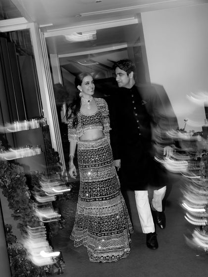 A motion-blur black and white shot of the couple walking at their Sangeet. This artistic photo captures the dynamic energy and excitement of the evening.