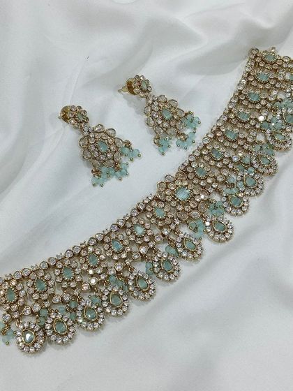 A beautiful choker set with pastel blue stones and a gold finish. This piece is perfect for pairing with modern lehengas or sarees for a subtle, elegant look.