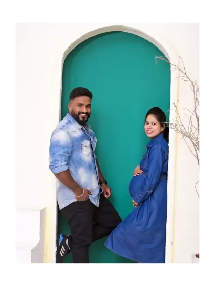 A fun and stylish pose with the couple in matching denim. The arched doorway with the pop of teal color creates a modern and visually interesting frame for their portrait.
