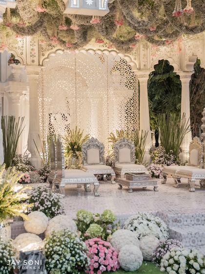 For this wedding, I designed a mandap that exudes ethereal elegance. It features intricate white jaali screens, ornate silver chairs for the couple, and a ceiling adorned with a thick layer of moss and hanging florals.