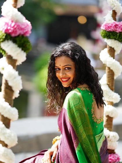 A joyful portrait of a woman on a floral swing, looking back at the camera with a bright, happy smile.