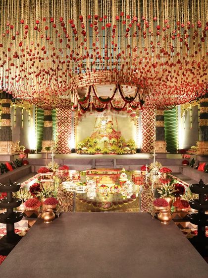 The central mandap area, reflected in the water feature. The ceiling is adorned with thousands of suspended flowers, creating a divine canopy above the sacred ceremony space.