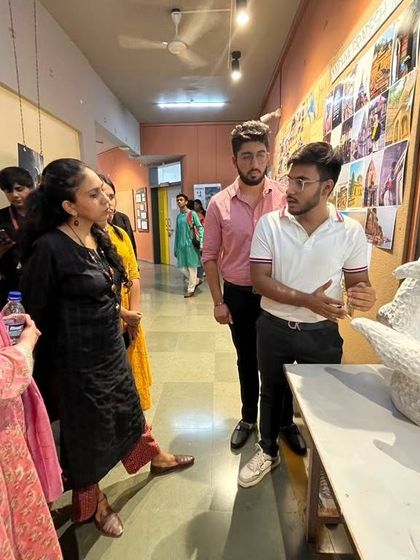 A student explains his sculptural model to visiting professors. These interactions are crucial for students to learn how to articulate their design concepts and receive valuable feedback from experienced professionals.