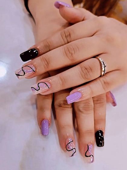 For the client who wants a bit of everything, I created this mismatched set. It combines solid black and lavender nails with clear extensions featuring freehand black swirl line art for a creative and personalized manicure.