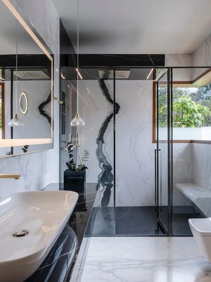 The bathroom is a luxurious retreat, with book-matched marble walls, a spacious glass shower, and elegant pendant lighting.