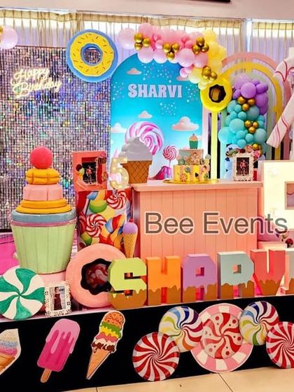 A wide shot of the vibrant Candyland-themed birthday stage. The setup is filled with colorful props like giant ice creams, donuts, and lollipops, creating a sweet and playful world for the birthday girl.