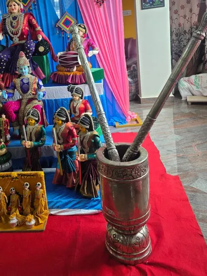 A close-up of a traditional silver mortar and pestle prop used in the Golu display.