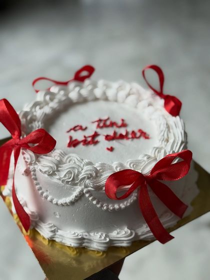 A vintage-inspired cake with delicate white piping and charming red ribbon bows. The custom message in the center makes it a personal and heartfelt gift.