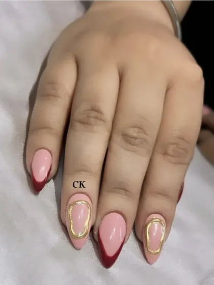 A modern and artistic take on the French manicure. This set features a deep red V-tip on some nails and abstract gold chrome outlines on others.