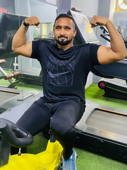 A client flexing his biceps after a workout. The smile shows the satisfaction of putting in the hard work.
