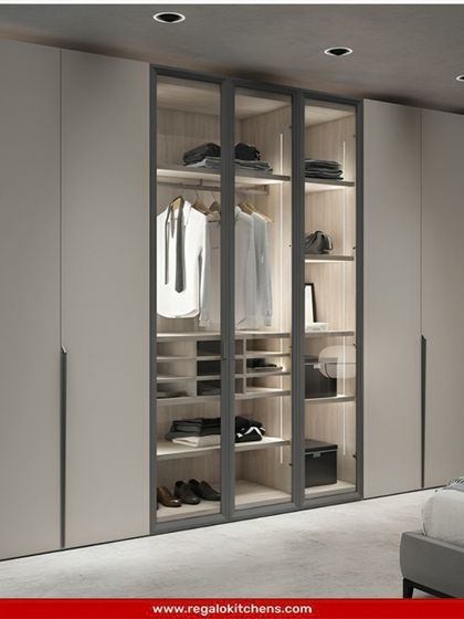 A clean and modern wardrobe design with handleless doors and a central glass display section. The combination of solid and transparent fronts adds visual interest.