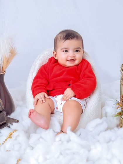 This little one is all smiles in our cloud-themed setup. The bright red sweater provides a beautiful pop of color against the white, fluffy background.