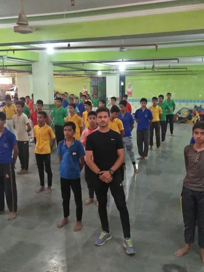 An instructor leads a line of students in a school hall during a workshop. Discipline and order are the first lessons we teach in any setting.