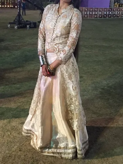 For a unique fusion look, we offer this ivory skirt set with a full-sleeve sheer embroidered jacket. It combines the grace of a traditional outfit with a modern silhouette, perfect for a cocktail party or reception.