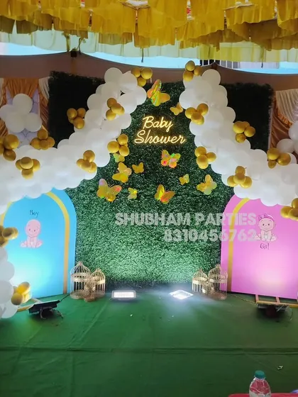 A unique baby shower stage with a grass wall backdrop and separate "Boy" and "Girl" themed arches.