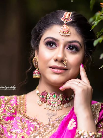 A close-up portrait of a model in a pink saree, wearing a beautiful kundan choker and maang tikka.