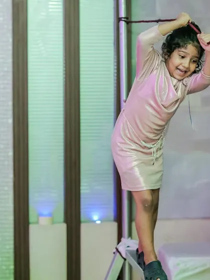 A young girl tackles a rope climbing challenge. Our adventure zones are designed to be both fun and safe, with soft landings and sturdy equipment.