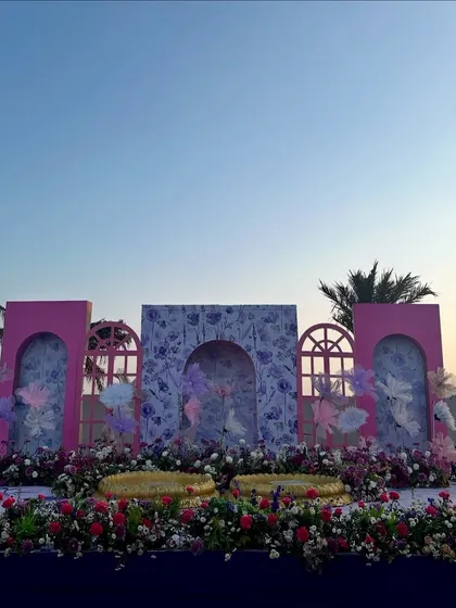 The main stage for a Haldi carnival at sunset, featuring a custom-built backdrop with pink and floral-printed arches.