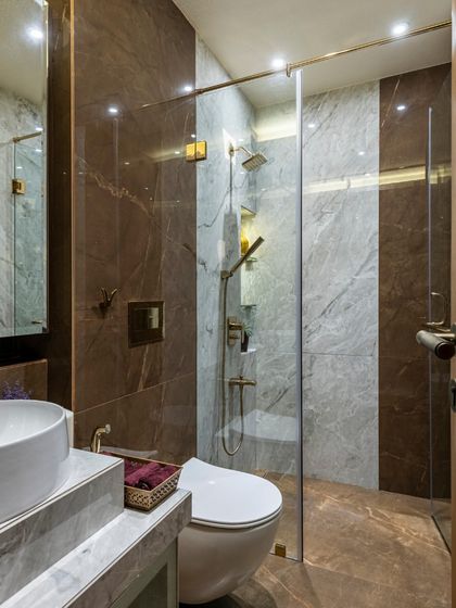 A stylish bathroom in the Filigree House, featuring a mix of brown and grey marble tiles. The design is modern and sophisticated, with a focus on clean lines and high-quality materials.