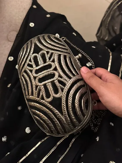 A detailed shot of the intricate metalwork on the clutch bag. I believe in investing in unique accessories that can elevate multiple outfits.