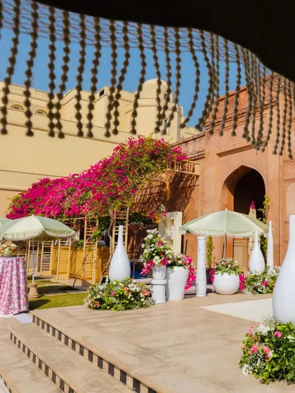 The view from the steps, showcasing the beautiful contrast between the historic fort architecture and our fresh, modern decor. Large white vases and pastel parasols add a touch of softness to the sun-drenched courtyard.