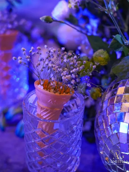 A playful detail from the event, featuring a small floral arrangement in an ice cream cone, placed next to a sparkling disco ball.