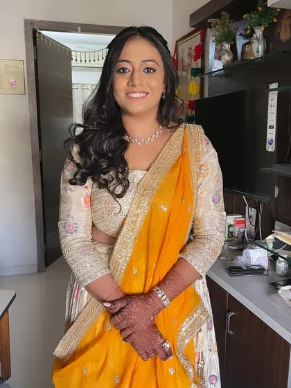 A full view of the engagement look. The makeup is elegant and polished, perfect for this important milestone. The soft curls and yellow and cream lehenga complete the look.