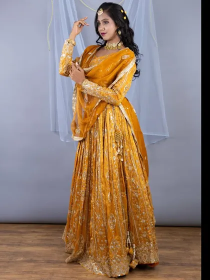 This shot captures the flow and texture of the heavily embroidered mustard yellow lehenga, perfect for a wedding or grand celebration.