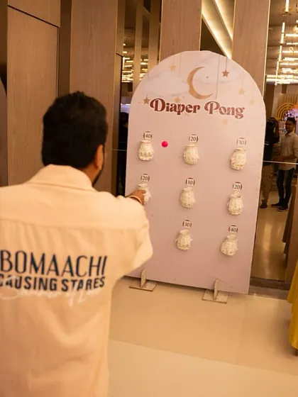 A guest trying his hand at Diaper Pong. The custom-made game board fits perfectly with the 'Oh Baby' theme of the event.