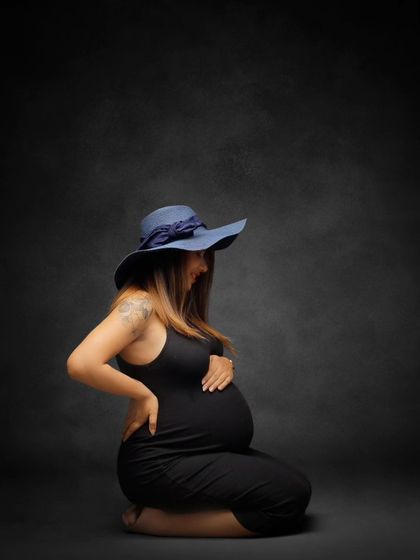 A stylish portrait in a simple black dress and a fashionable blue hat. This shot shows that maternity photos can be chic and modern.