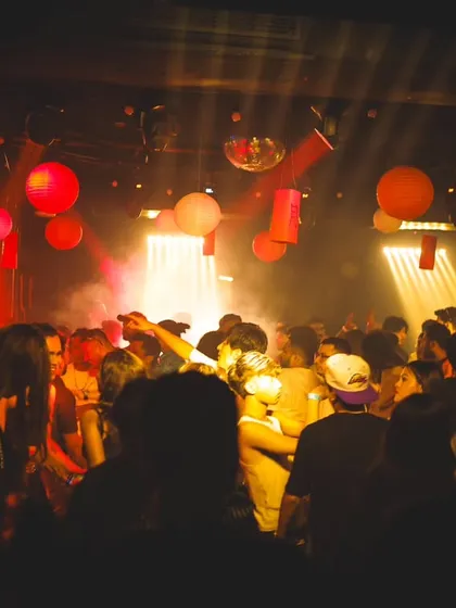 A packed dance floor under red lights and lanterns during 'Asian Night'. The atmosphere was incredible, and the crowd was ready to party.
