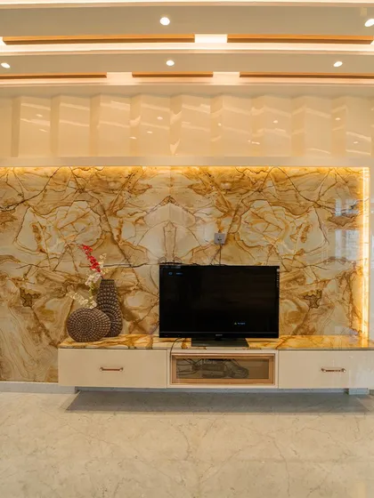 The TV unit wall is clad in bookmatched onyx marble, which glows warmly when backlit, turning a functional wall into a piece of art.