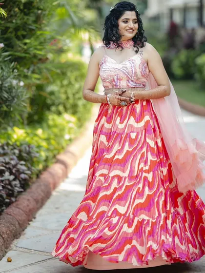 This Haldi hairstyle features natural curls in a half-updo, adorned with a small floral accessory. It's a fun, fresh, and practical style that keeps the hair managed during the ceremony.