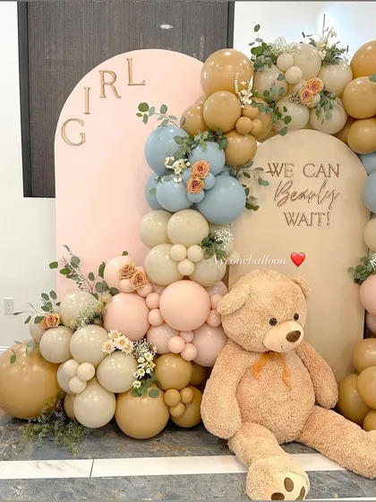 The teddy bear theme is a classic for a reason. Here is a gender reveal setup with the message 'We Can Bearly Wait', using a soft, modern palette of muted blue, pink, and beige balloons.