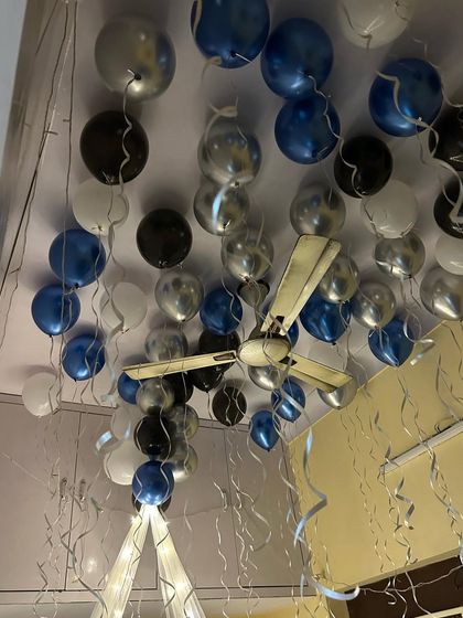 A canopy-style birthday setup using blue, black, and silver balloons floating on the ceiling, creating a cool and modern celebratory vibe.