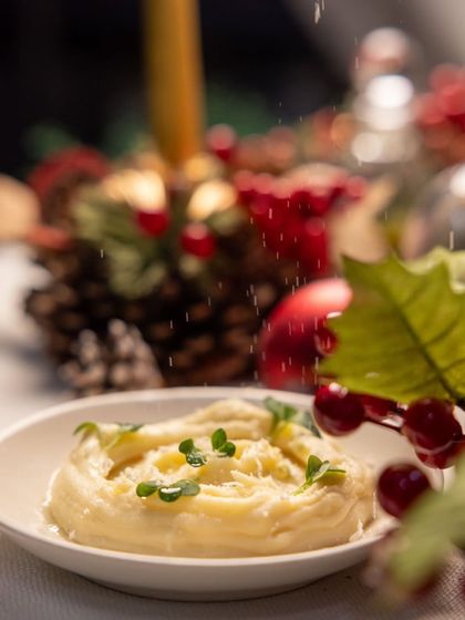 A dusting of parmesan cheese falls like snow onto a creamy potato mash, a comforting classic for the holiday season.
