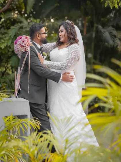 A lovely candid moment on a bridge, surrounded by lush greenery. The couple is lost in their own world, making for a natural and romantic portrait.