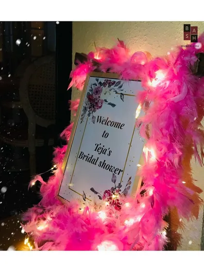 It's all in the details. This personalized welcome sign for Teja's bridal shower is wrapped in a bright pink boa and fairy lights, setting a glamorous and fun tone right from the entrance.