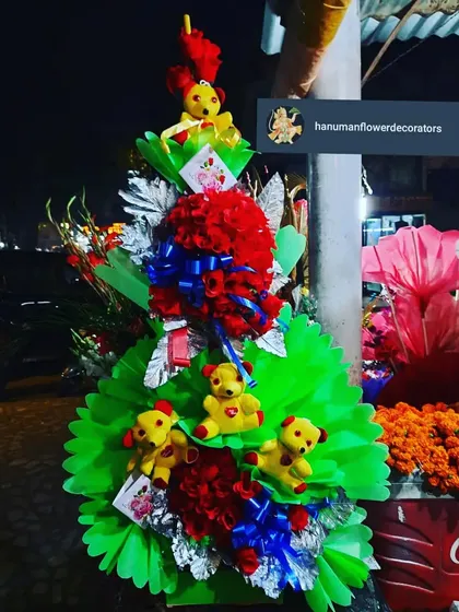 For a unique and playful gift, I designed this multi-tiered arrangement. It features bright red floral spheres, festive ribbons, and several small yellow teddy bears, creating a memorable and cheerful display.