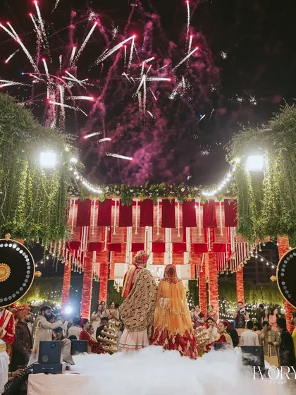 The moment of union, set against a sky lit with fireworks. We use creative angles to show the scale of the celebration, with the couple enveloped in ethereal smoke on stage.