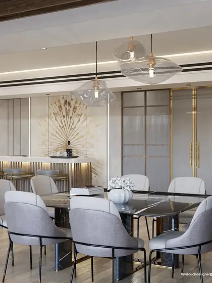 This luxurious dining room features a large marble table and comfortable upholstered chairs, set under unique, organically shaped glass pendant lights. An integrated bar area in the background makes it ideal for entertaining.