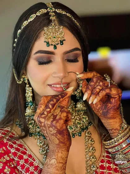 A delicate and beautiful shot of the bride adjusting her nath. This angle shows off the detailed eye makeup and the intricate henna design.